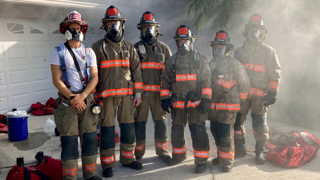 Group of firefighters outside a house in full gear.