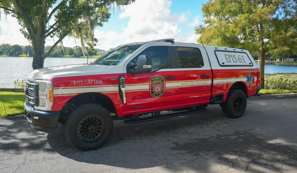 EMS 61 parked on the street in front of a lake and trees.